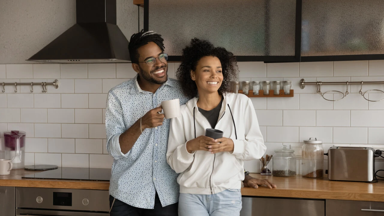 A couple holding coffee mugs looking at their renovated kitchen.