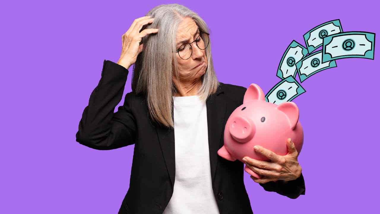 Grey-haired woman looking at a pig-shaped piggy bank.