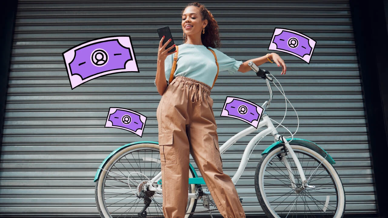Woman leaning against a bicycle looking at a mobile phone.