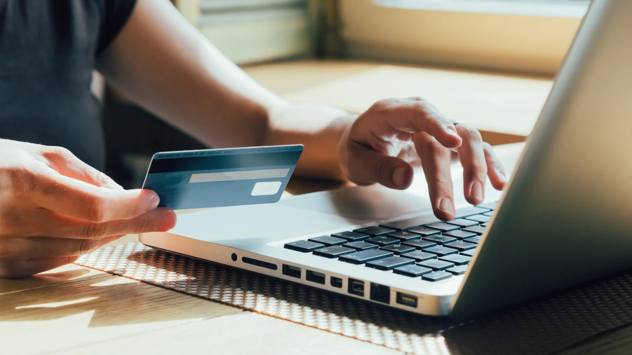 Person using their credit card to make a purchase on their laptop. 