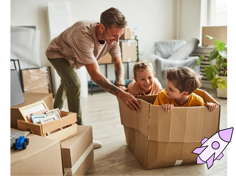 A parent pushing children in a moving box across a room. 