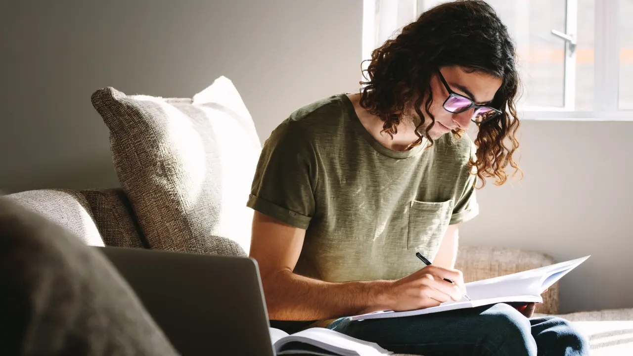 Young man studying on a couch.