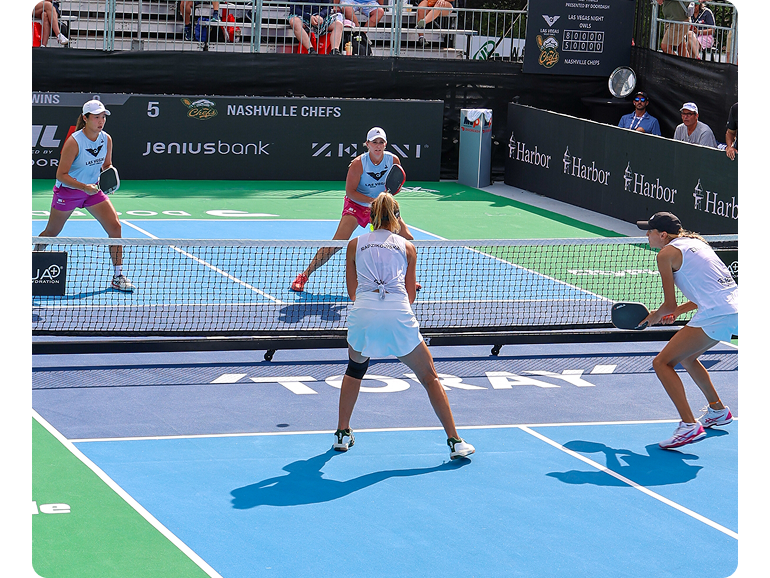 Women’s doubles pickleball players engage in a rally. 