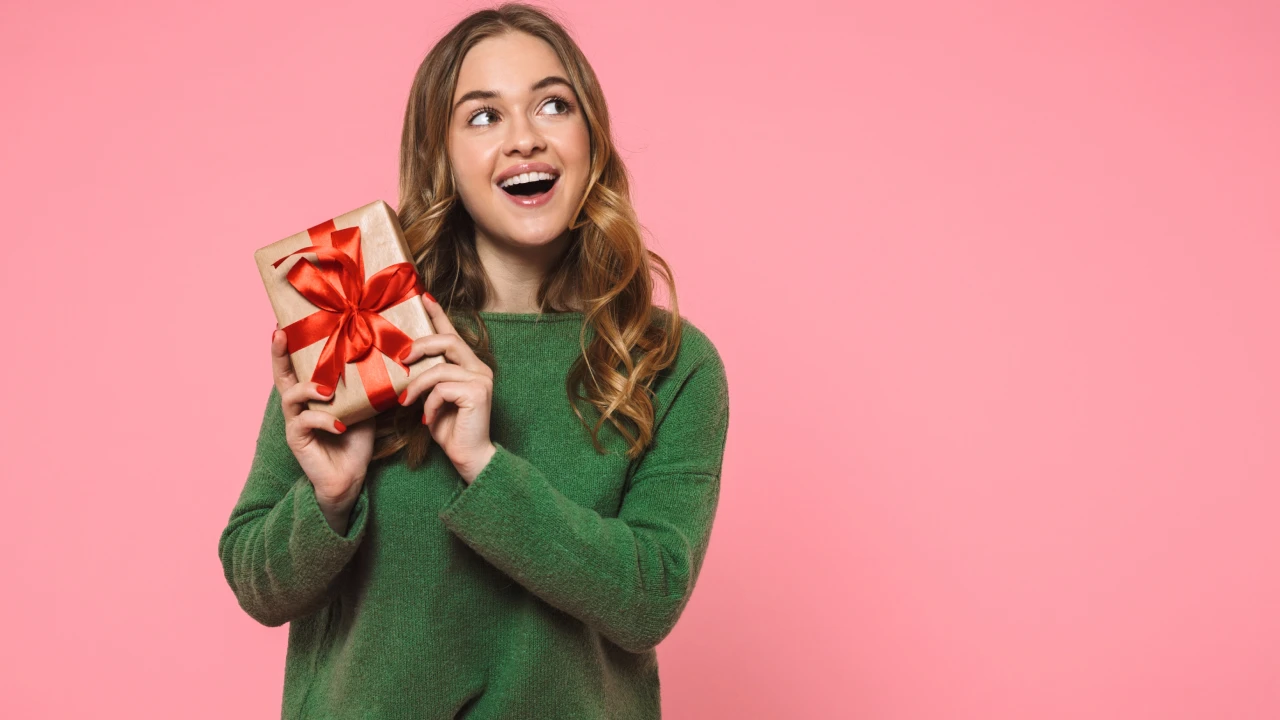 A young woman holding a present, looking happy.
