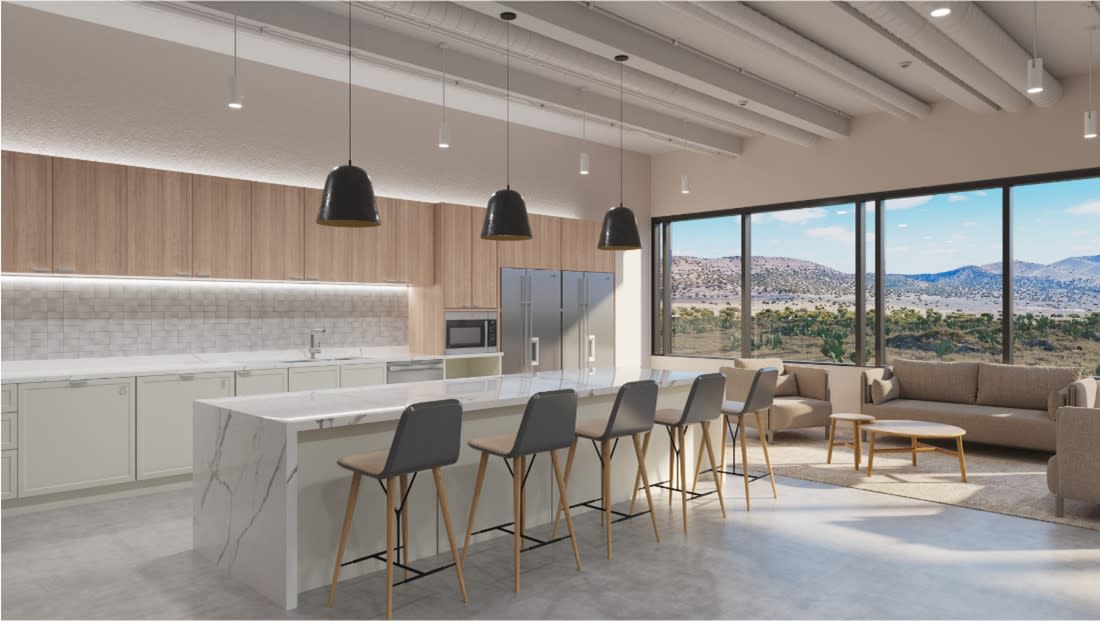 Open-concept breakroom with soft seating, a counter with counter chairs, and a kitchen space.