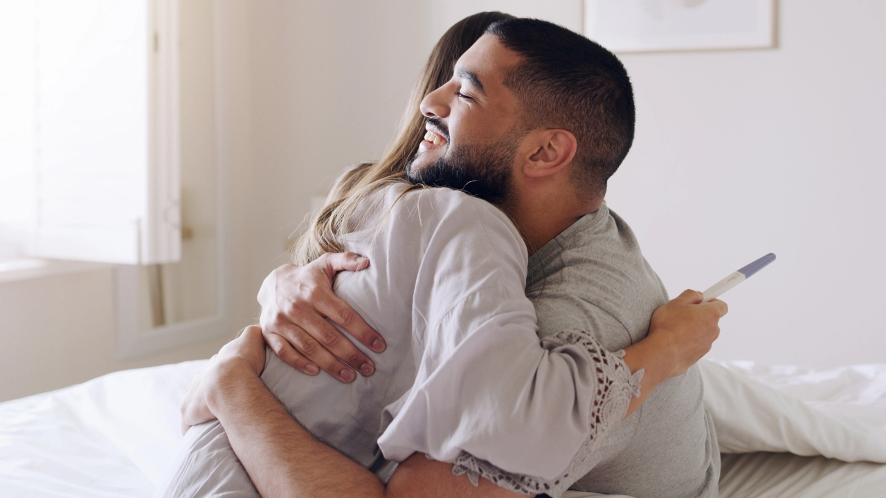 A couple embracing while holding a pregnancy test. 