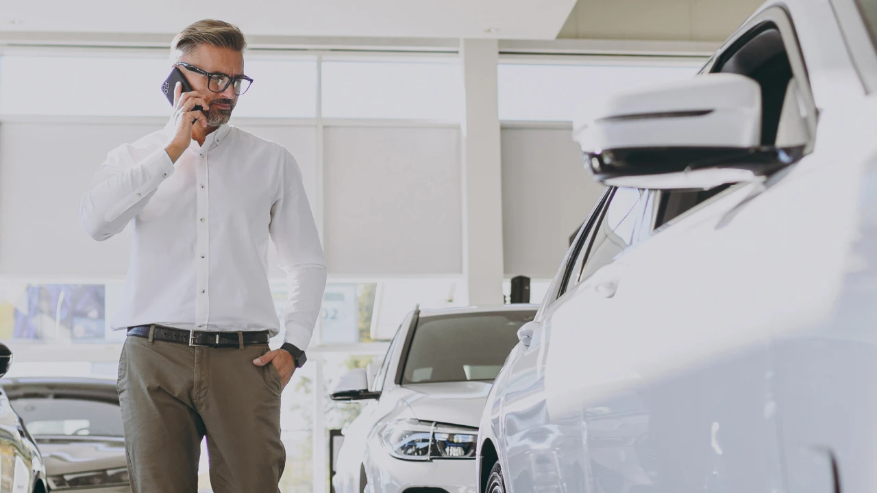 A person talking on a cell phone in a car showroom.
